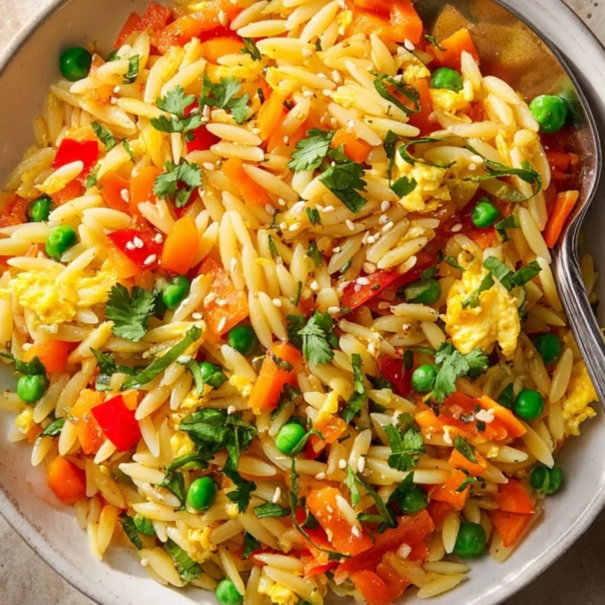 Close-up of delicious Orzo Fried Rice Style, garnished with sesame seeds and fresh herbs.