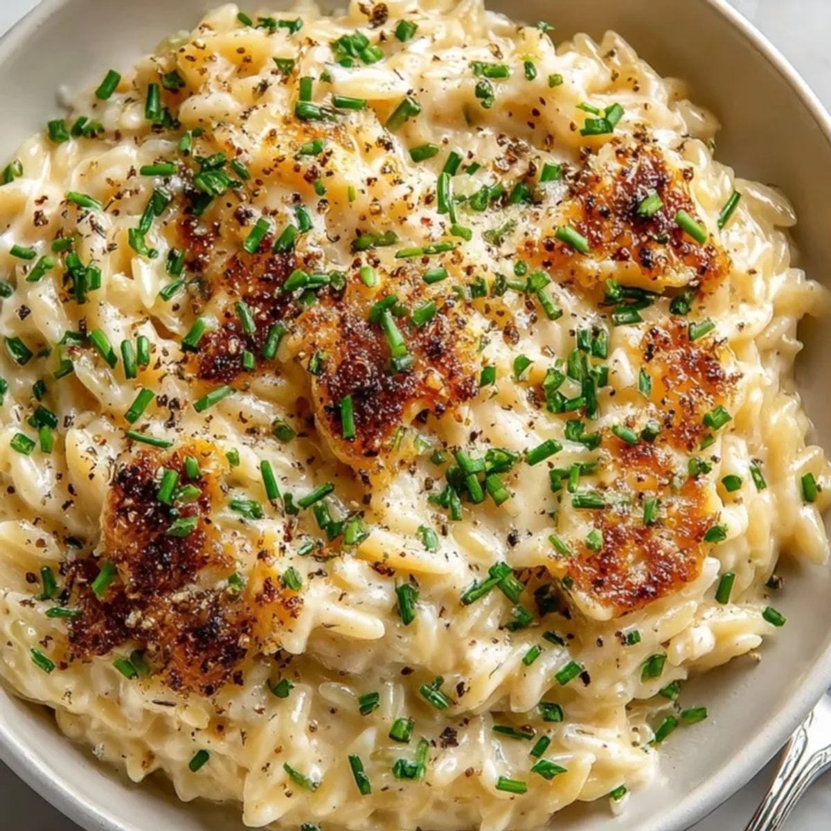 Creamy Parmesan Truffle Orzo, glistening with truffle oil and a sprinkle of fresh herbs.