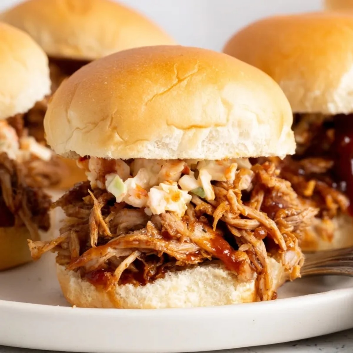 Close-up of juicy Spiced Cider Pulled Pork Sliders piled high, ready to eat.