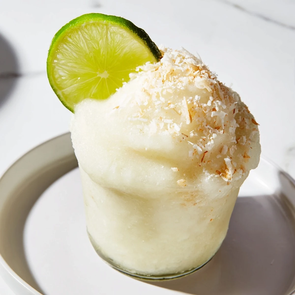 Vibrant lime garnish tops a beautiful White Christmas Margarita Slush, a fun and easy party drink.