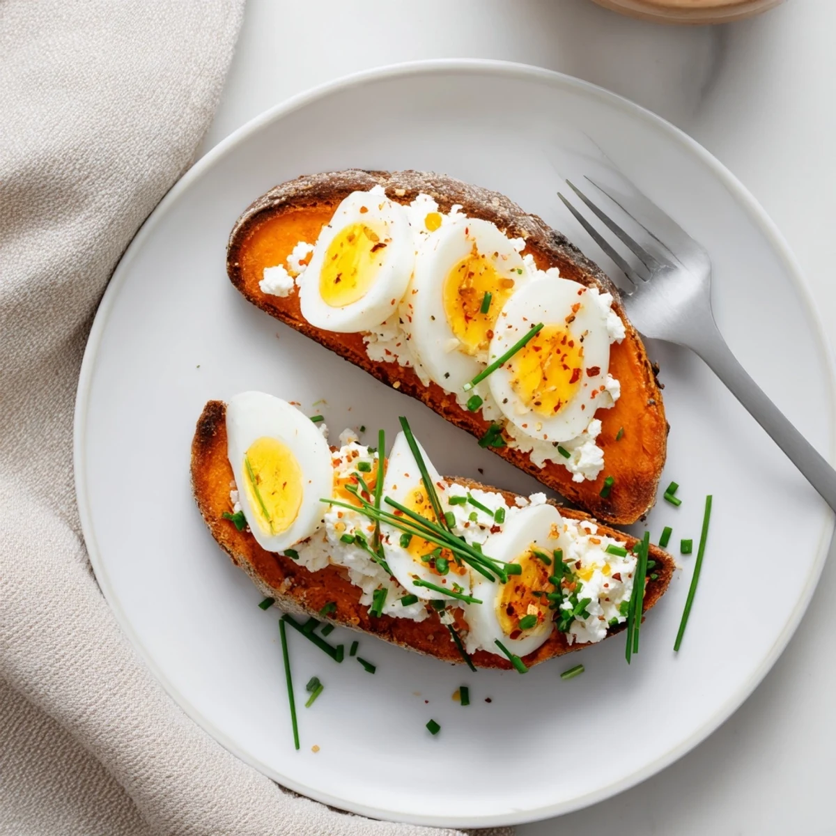 Roasted sweet potato toast variations topped with sliced avocado, cherry tomatoes, and fresh herbs on a rustic plate.