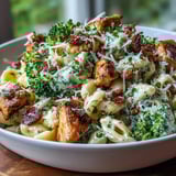 Savory Garlic Parmesan Broccoli & Chicken Pasta steams beside a glass of crisp white wine.