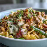 Spoon lifting a creamy serving of Creamy Ranch Turkey & Veggie Skillet from a cast-iron pan, revealing tender bell peppers, corn, and melted cheddar cheese.