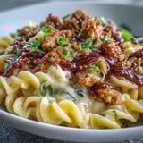 A fork digs into cheesy elbow macaroni mixed with Korean-style turkey, showcasing the rich, spicy, and comforting fusion dish.