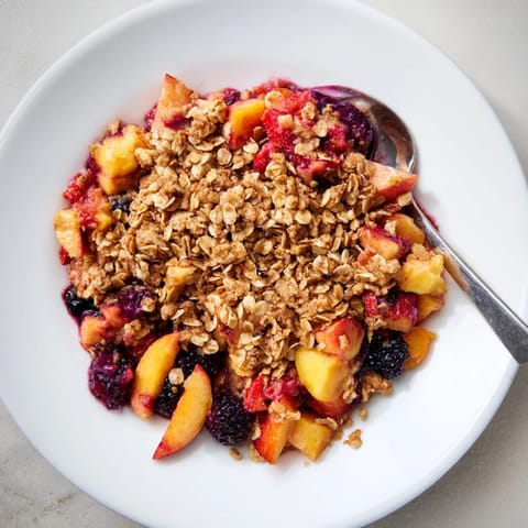 A scoop of vanilla ice cream next to the warm fruit crisp with oats, a delightful treat.