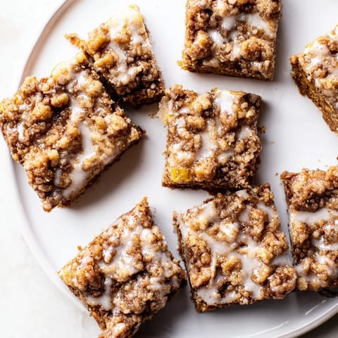Warm gingerbread bars, visible with a beautiful lemon glaze, offering a delightful crumble topping.