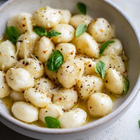 Fresh, seasoned mozzarella pearls served in a small bowl, ready for a light and delicious snack.