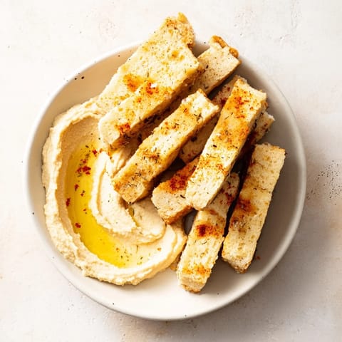 Freshly baked rosemary Holiday Crackers, crisp and flavorful, are arranged with a dip of homemade hummus.