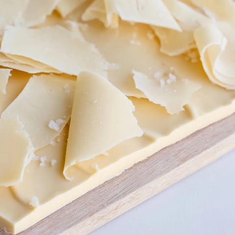 A chilled wooden board presents the delicate Arctic Tundra dessert with melting white chocolate sheets.