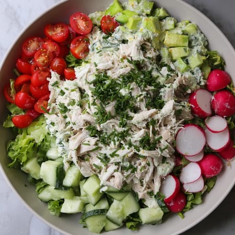 Vibrant Green Goddess Chicken Nacho Dip with colorful vegetables, served next to a bowl of golden tortilla chips.
