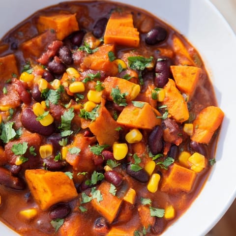 Steaming Smoky Sweet Potato Chili with vibrant peppers and cilantro, ready to be served.
