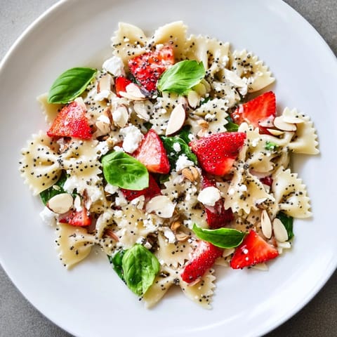 This Spring Spinach Strawberry Pasta Salad showcases tender pasta, juicy strawberries, and a flavorful dressing in a salad bowl.