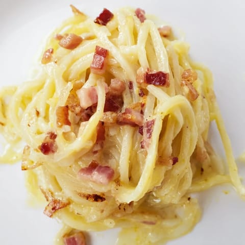 Steaming celeriac carbonara in a skillet, featuring low-carb spiralized noodles and rich egg-cheese sauce.  