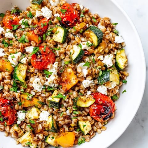Freshly prepared Farro With Roasted Vegetables served warm, showcasing tender carrot slices and red onion wedges on a rustic plate.