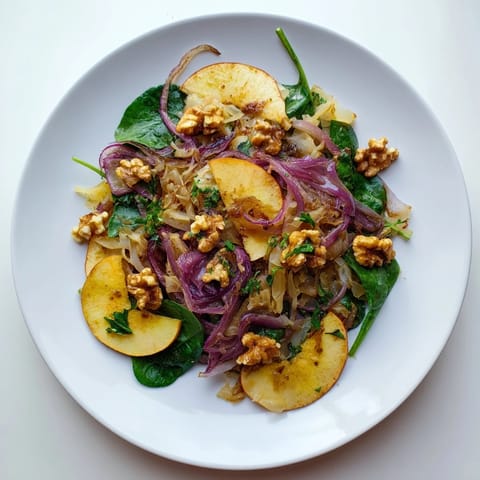 Close-up of Warm Apple and Sauerkraut Skillet Salad in a skillet, showing tender apples and sauerkraut glistening with olive oil and fresh parsley.