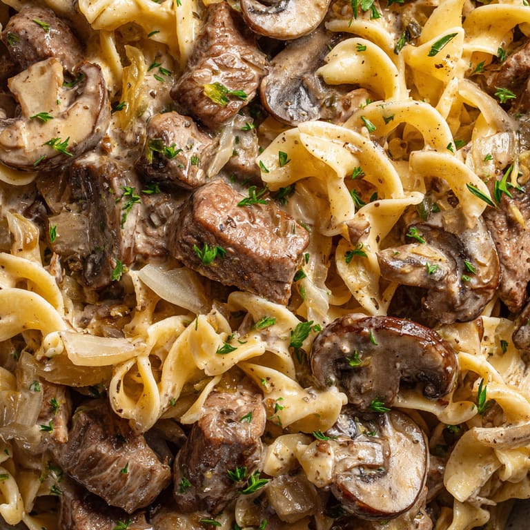A close up of a plate of pasta with mushrooms and meat.