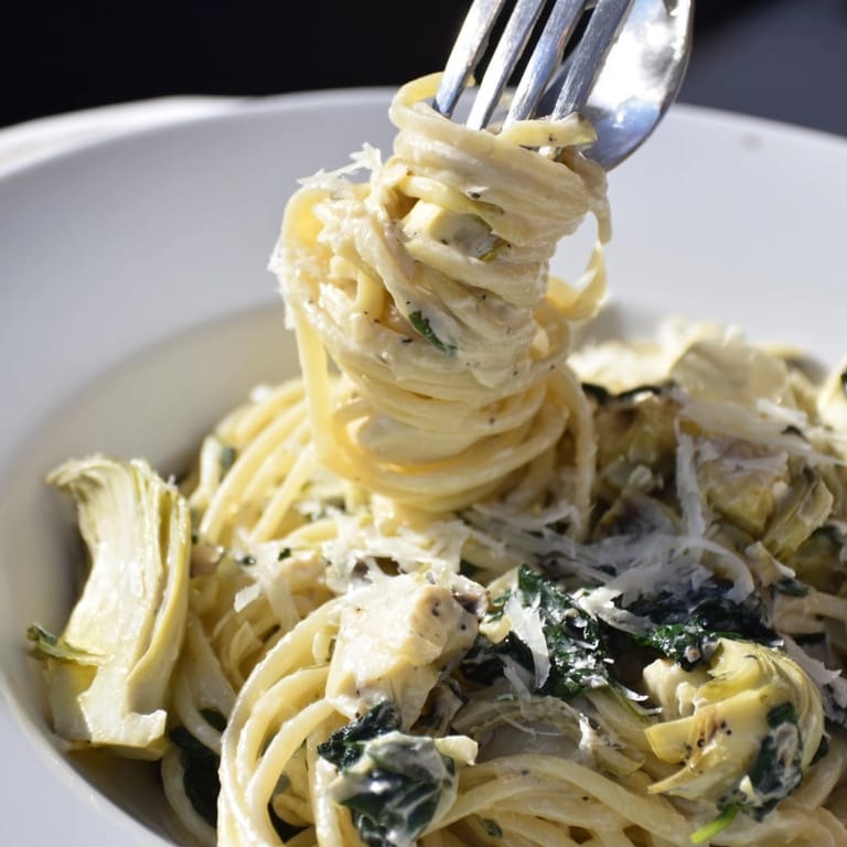 Close-up of Creamy Spinach Artichoke Spaghetti, garnished with fresh parsley and Parmesan.