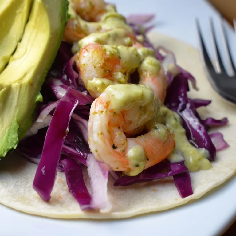 Vibrant Lemon Herb Shrimp Tacos embraced by tortillas, drizzled with rich cilantro sauce.