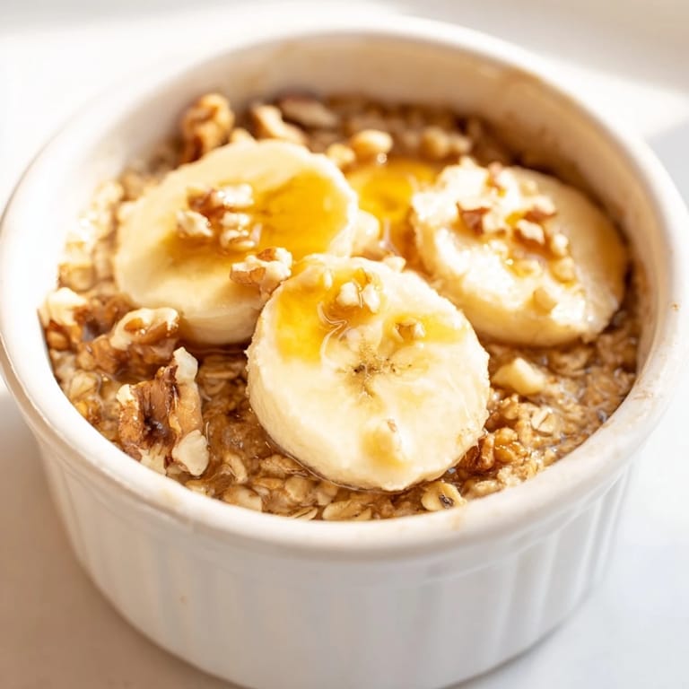 Individual ramekins of baked oats, topped with sliced bananas and drizzled honey, a delicious way to start your day.