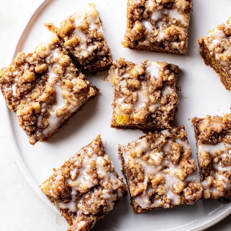 Warm gingerbread bars, visible with a beautiful lemon glaze, offering a delightful crumble topping.
