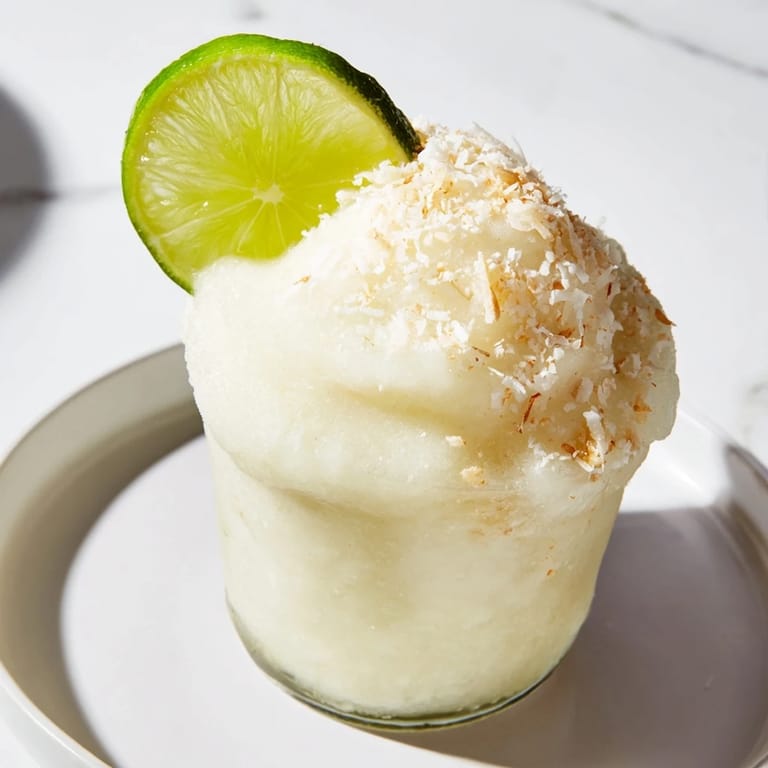 Vibrant lime garnish tops a beautiful White Christmas Margarita Slush, a fun and easy party drink.