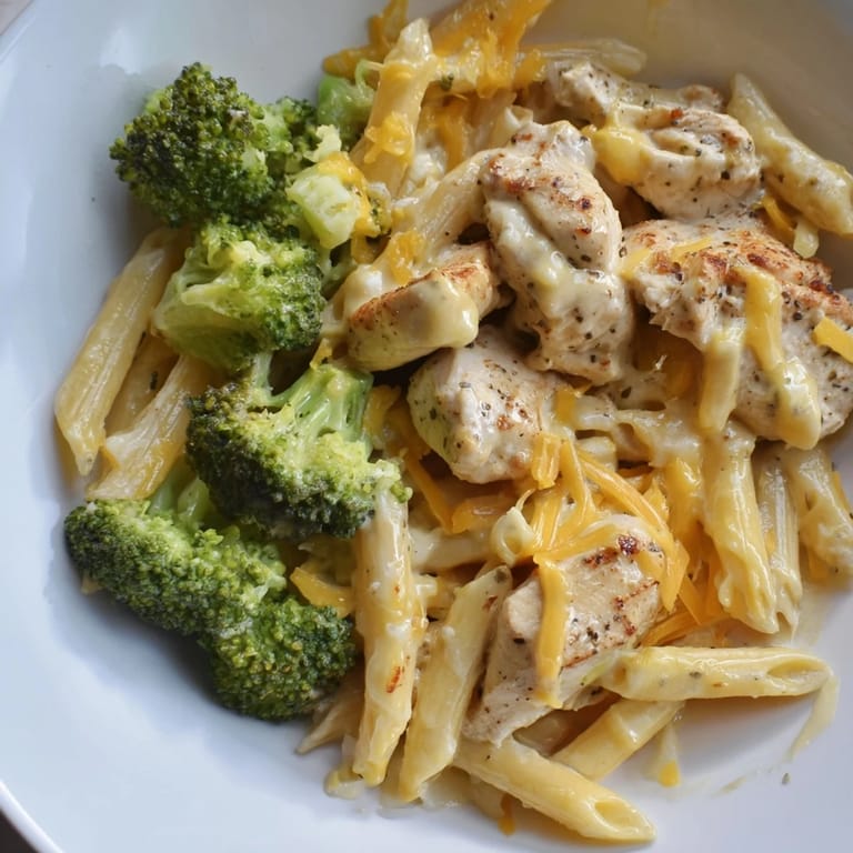 A steaming bowl of Chicken Broccoli Cheddar Pasta, showcasing the vibrant broccoli and cheddar cheese.