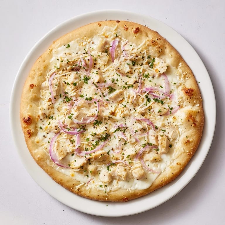 Delectable Chicken Alfredo Pizza, a generous slice featuring savory chicken, served on a white plate.