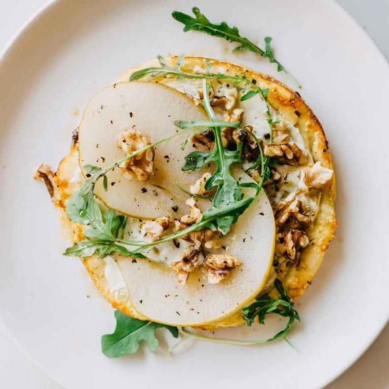 Perfect for a party spread, these warm Pear, Gorgonzola, and Pickled Walnut Pizzettes are ready to serve.