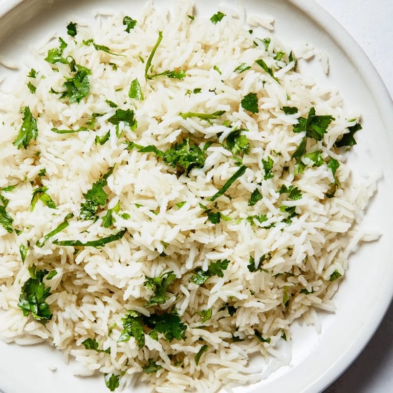 A bowl of aromatic Cilantro Lime Rice garnished with bright green herbs and a wedge of lime, ready to accompany your favorite tacos.