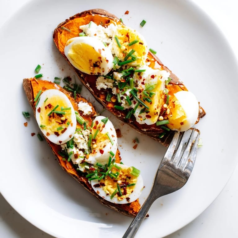 Savory sweet potato toast variations with hummus, crumbled feta, and chili flakes, served warm on a wooden board.