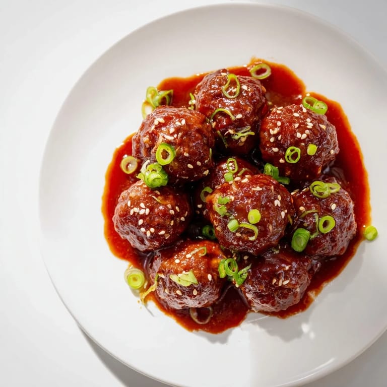 Tender Easy Sweet and Sour Crock Pot Meatballs served over steamed rice, with a tangy apricot sauce pooling on the plate.