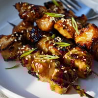 Tender ginger teriyaki chicken skewers caramelized on the grill, served with fresh herbs.  